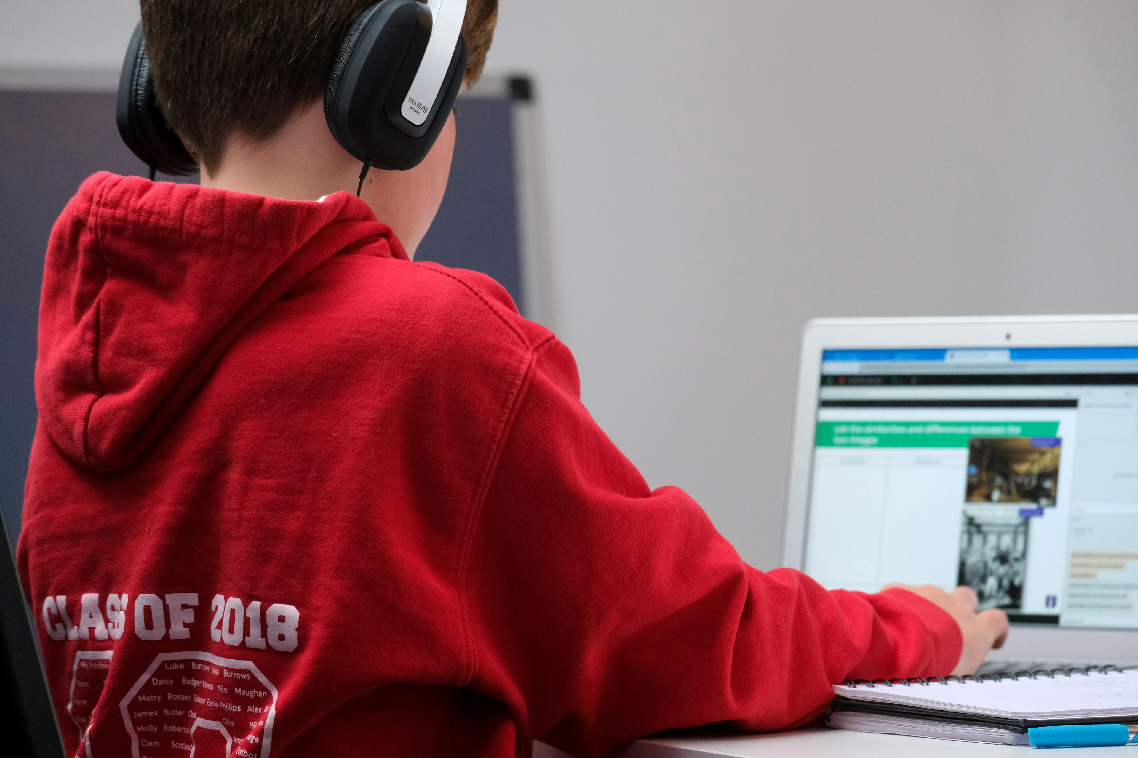 Boy working on school work with laptop and headphones